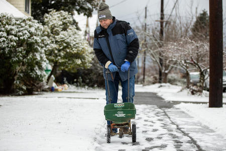 A man works on a snowy sidewalk