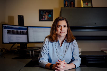Sadie Armijo, of the State Auditor's Office, sits at her desk in her office with her hands together in front of her. 