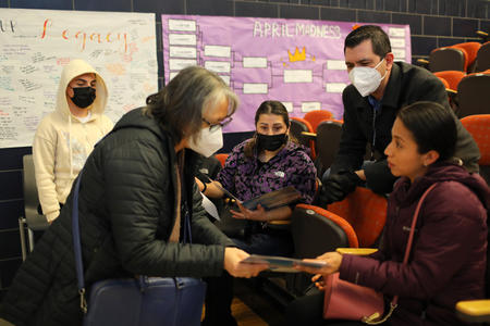 A school administrator helps a parent while a language interpreter facilitates their conversation