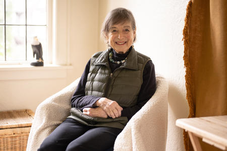 Person in chair with hands folded on lap, window nearby brings soft light in