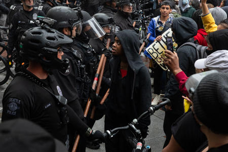 Protesters stand before a line of police