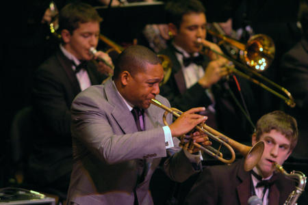 A man in a suit plays the trumpet