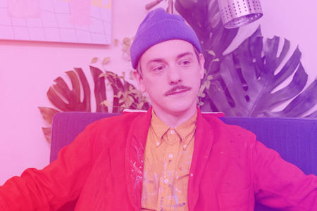 A man sitting down looks off into the distance with a purple/pink filter over him