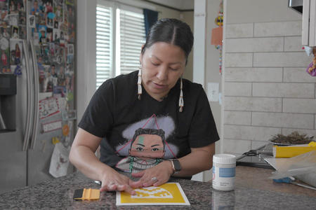 Still of Lorelei Kruger working with a stencil on canvas