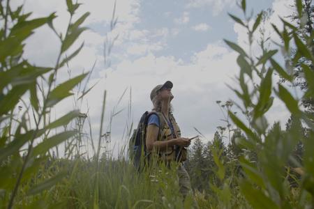 woman standing in the reeds with a notebook in hand