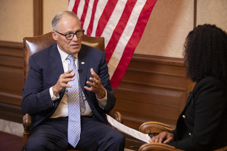 Gov. Inslee sitting in front of an American flag