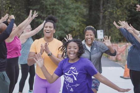 Women and girl running while people cheer around them