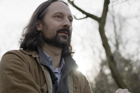 person with tree branch behind him staring into distance