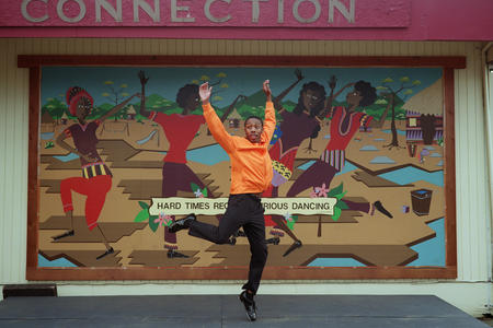 Cipher Goings dances in front of a colorful mural at the Northwest Tap Connection