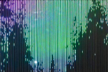 digital art installation that looks like dark evergreen trees lit by the shifting colors of the aurora borealis