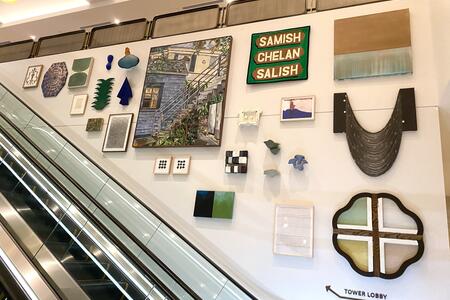 photo of an escalator next to a wall of many different small artworks