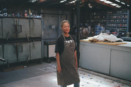 Debora Moore wears an apron standing in her glassblowing art studio