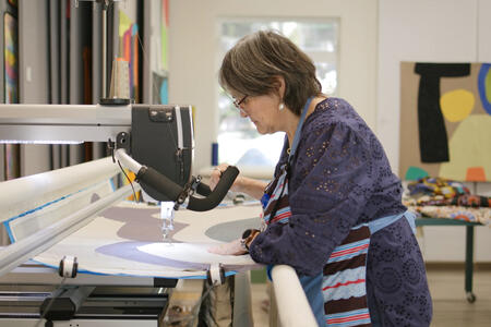 Julie Sevilla Drake operates her long arm machine, a moving apparatus that allows her add playful stitching across her quilts