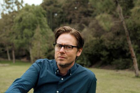 Tim Heidecker sits in front of trees