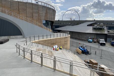 photo of a swooping concrete sidewalk and amphitheater with construction workers in progress