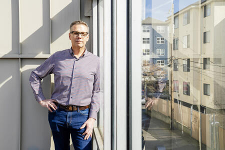 man poses for photo by large window