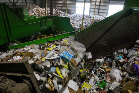 Assorted trash goes through a large machine.