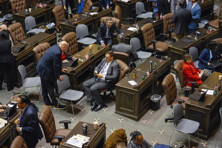 Lawmakers sit at desks on the House floor.