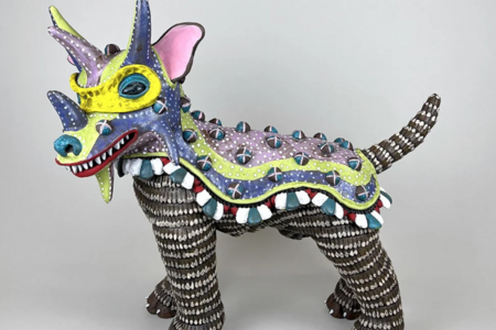 A ceramic sculpture of a dog with goat horns covered in colorful tile