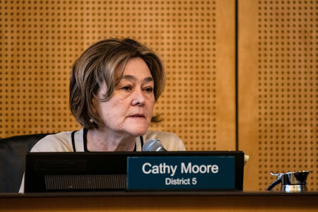 a woman sits behind the dais in seattle city council chambers 