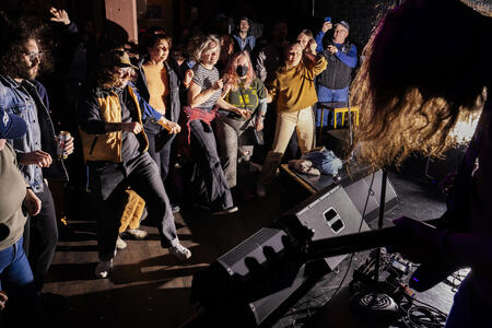 A crowd of people dances on the floor of a music venue. 