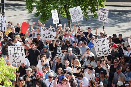 a crowd of people waving signs outside seattle city hall
