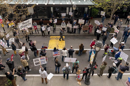 A protest seen from the top down. Dozens of people gather in a street.