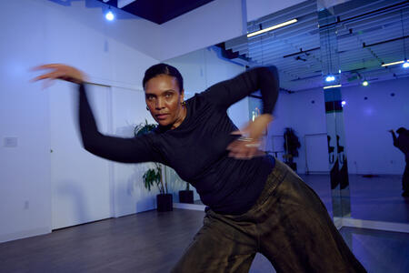 a Black woman dances in a rehearsal studio