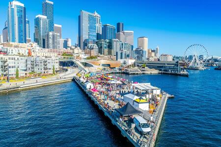 offshore photo of a cityside pier jutting out into the water with tents and people on it