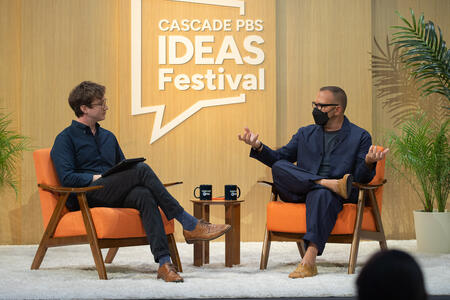Two men sit on chairs at the Cascade PBS Ideas Festival