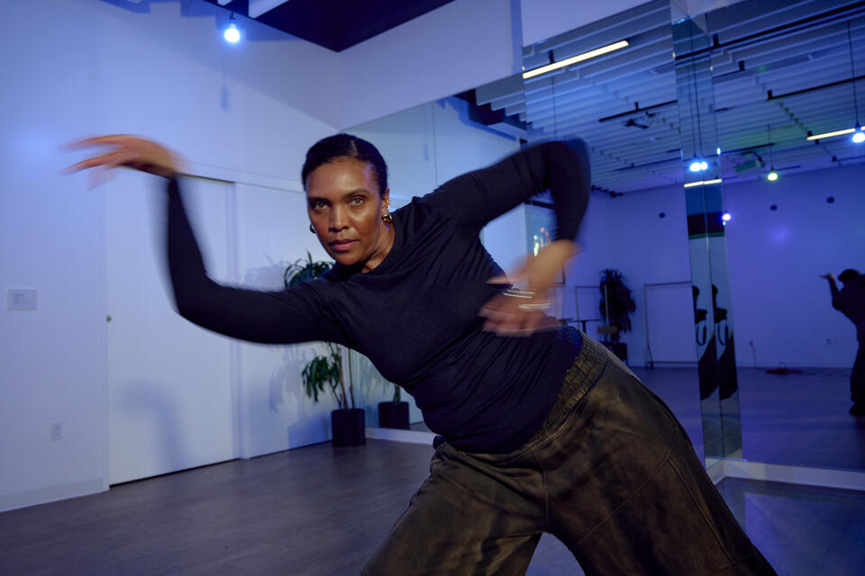 a Black woman dances in a rehearsal studio