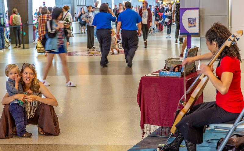 A little boy and his mother watch a woman play the cello at the SeaTac Airport